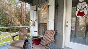 A wooden deck with two Adirondack chairs, a red planter, and a snowman decoration on the door. - Bass Ranch, just behind Bird Island. The perfect spot for Great Bass Fishing ! (Carriere)