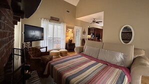 A bedroom with a large bed, a TV, a ceiling fan, and a fireplace. - Bass Ranch, just behind Bird Island. The perfect spot for Great Bass Fishing ! (Carriere)