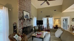 A living room with a brick fireplace, a ceiling fan, a Christmas tree, and a television. - Bass Ranch, just behind Bird Island. The perfect spot for Great Bass Fishing ! (Carriere)