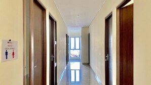 Un pasillo con puertas a ambos lados, un letrero que indica distanciamiento social y una ventana al final.