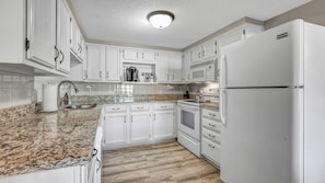 A kitchen with white cabinets, a granite countertop, a built-in oven, and a refrigerator. - Firefly Cottage; Prime Cove location, large dock, grill, screened in porch  (Lake Ozark)