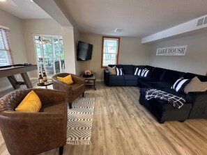 A living room with a pool table, leather armchairs, a dark sofa, and a sign reading "LAKE HOUSE". - Firefly Cottage; Prime Cove location, large dock, grill, screened in porch  (Lake Ozark)