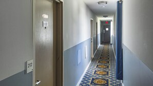 A hotel hallway with a patterned carpet, doors numbered 212, and a blue curtain on the right. - Sunrise Inn Hershey (Hershey)