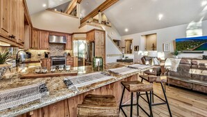 A spacious kitchen with a large island, wooden cabinets, and a stone backsplash.