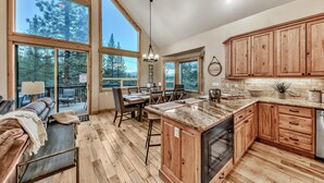 A spacious kitchen with large windows, wooden cabinets, and a granite countertop.