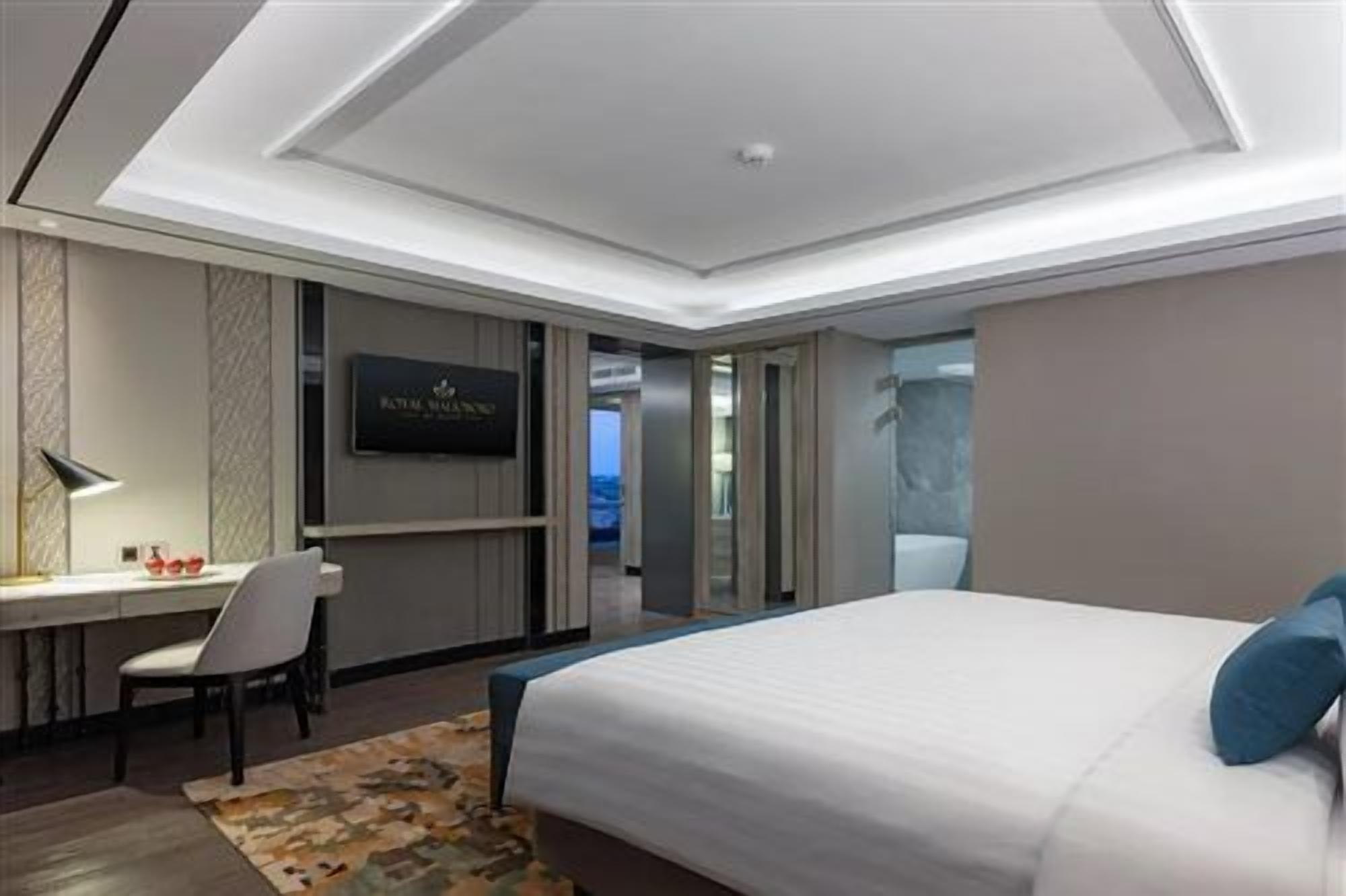A hotel room with a bed, desk, chair, and a television.