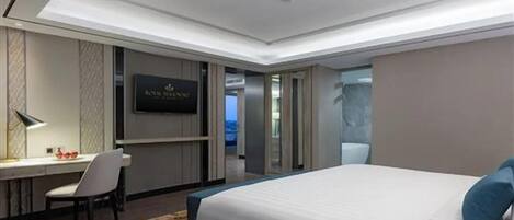 A hotel room with a bed, desk, chair, and a television.