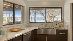 A kitchen with a large window, a stainless steel sink, and a marble countertop. - NOW ACCEPTING ONE YEAR LEASES ON OUR WATERFRONT HOME! (Merritt Island)