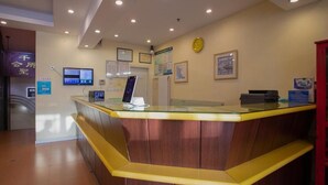 A reception desk with a glass top, wooden paneling, and a digital display.