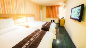 A hotel room with two beds, a television, a desk, and a window with curtains.