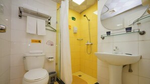 A bathroom with a toilet, a sink, and a shower area.