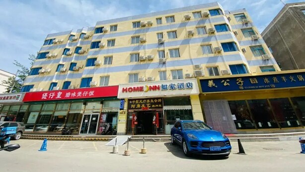 A multi-story hotel with a red and yellow facade, featuring a prominent 'HOME' sign.