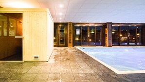 Ein Poolbereich mit Innenbereich, einer Holztresen, Glastüren und Fliesenböden.