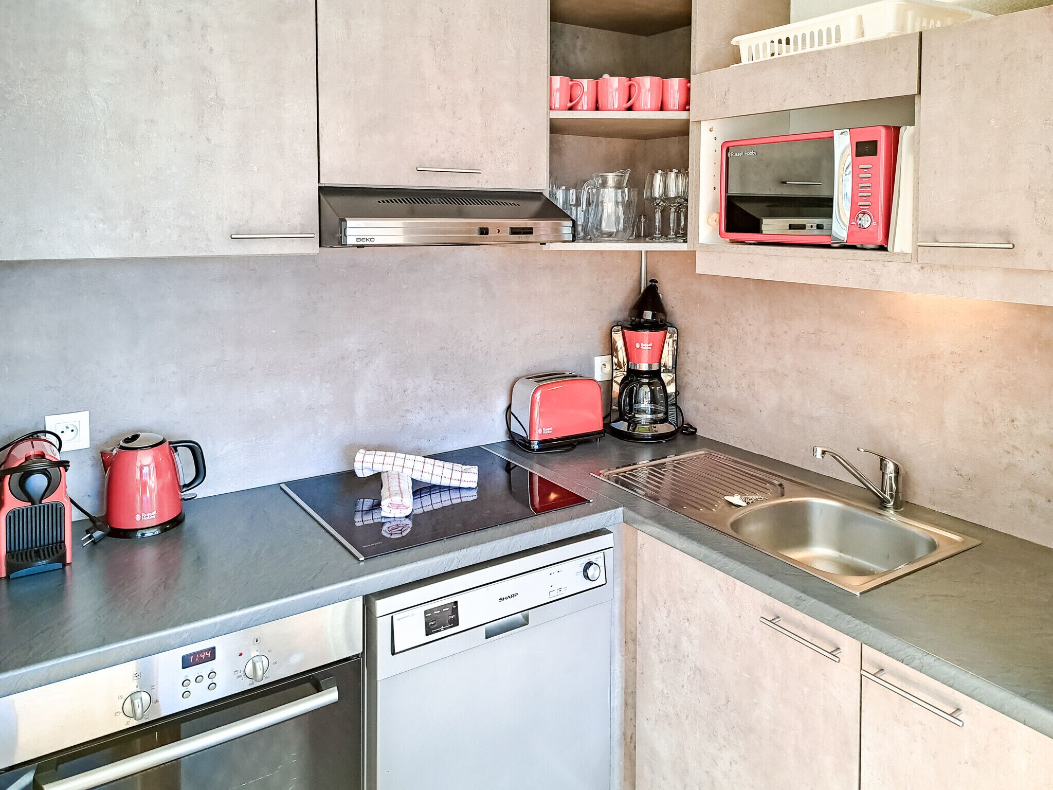 A compact kitchen with a built-in oven, a coffee maker, a toaster, and a microwave.