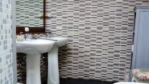 Ein Badezimmer mit zwei Waschbecken, einer Toilette und einem gemusterten Teppich.