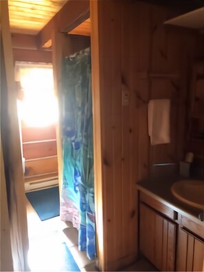 A wooden cabin interior with a bathroom featuring a sink and a towel hanging on the wall. - Waterfront Log Home, WiFi, 3 bedrooms, Direct TV, Fire Pit (Egg Harbor)