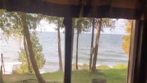 A view from a window with a view of a grassy area and a body of water.