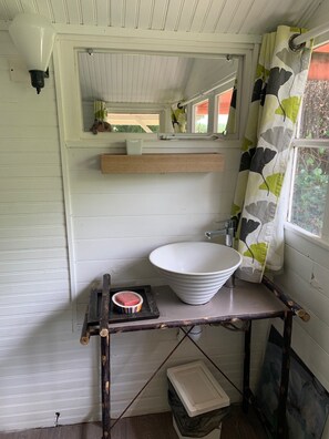 Een badkamer met een witte wastafel, een houten plank en een spiegel erboven.