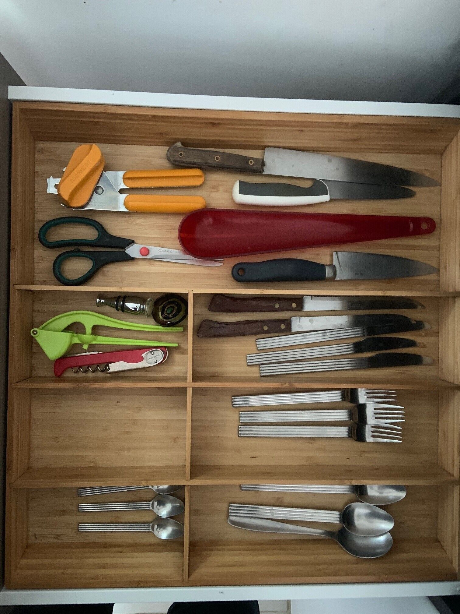 Eine Schublade mit verschiedenen Küchenutensilien, darunter Scheren, Messer und Löffel.