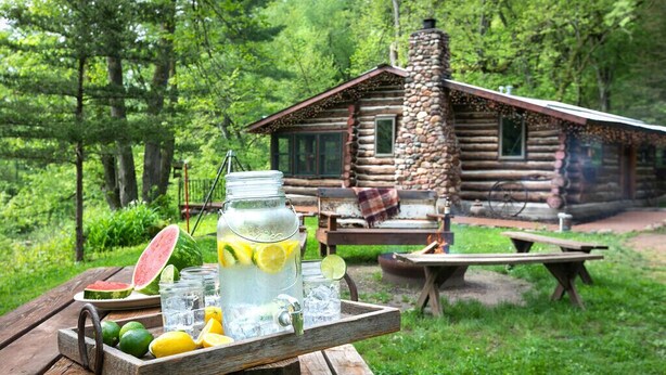 Eine rustikale Holzhütte mit einem Steinkamin, umgeben von üppiger Vegetation.