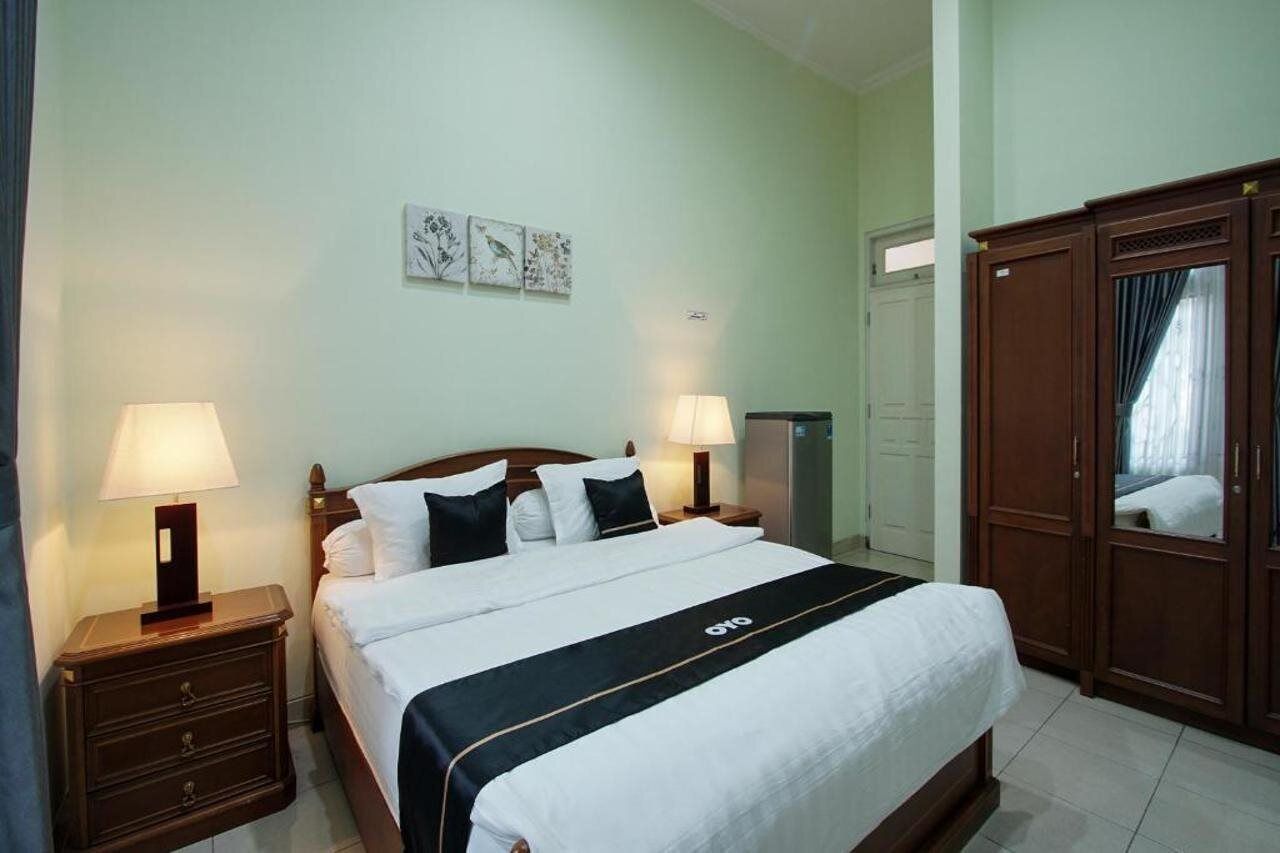 A hotel room with a bed, two bedside tables with lamps, a wardrobe, and a door.