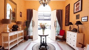 A hotel lobby with a round table, a potted plant, and a red chair. - OYO 3986 Just 11 Boutique Residence Syariah (Ngaglik)
