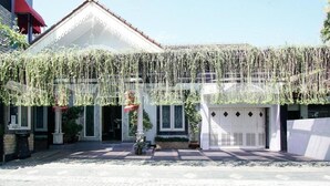 A building with a white facade, a red awning, and hanging plants. - OYO 3986 Just 11 Boutique Residence Syariah (Ngaglik)