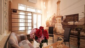 A hotel lobby with a sofa, chairs, a table with a vase of flowers, and a mural of a tower. - OYO 3986 Just 11 Boutique Residence Syariah (Ngaglik)