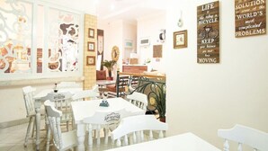 A café with white furniture and framed pictures on the walls. - OYO 3986 Just 11 Boutique Residence Syariah (Ngaglik)