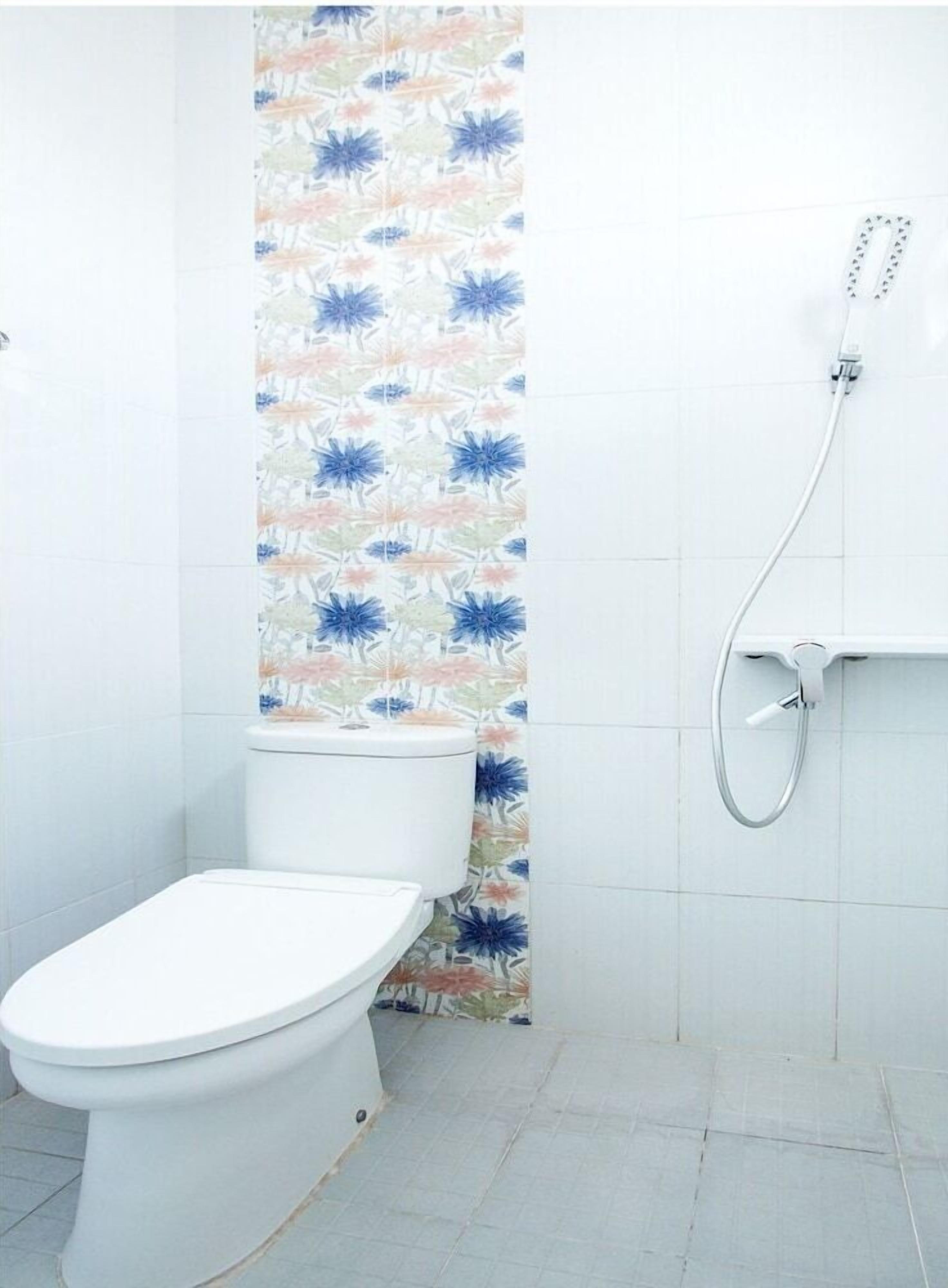 Un baño con inodoro, ducha y cortina de ducha con estampado floral.