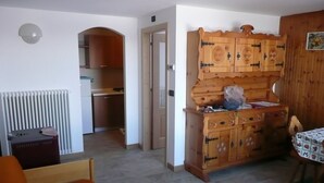 Un espacio habitable compacto con kitchenette, un armario de madera y una zona de comedor.