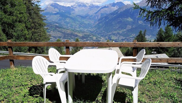 Mesa y sillas dispuestas al aire libre con vistas a la montaña.