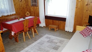 Una habitación acogedora con detalles de madera, una mesa de comedor con sillas, un sofá y un televisor.