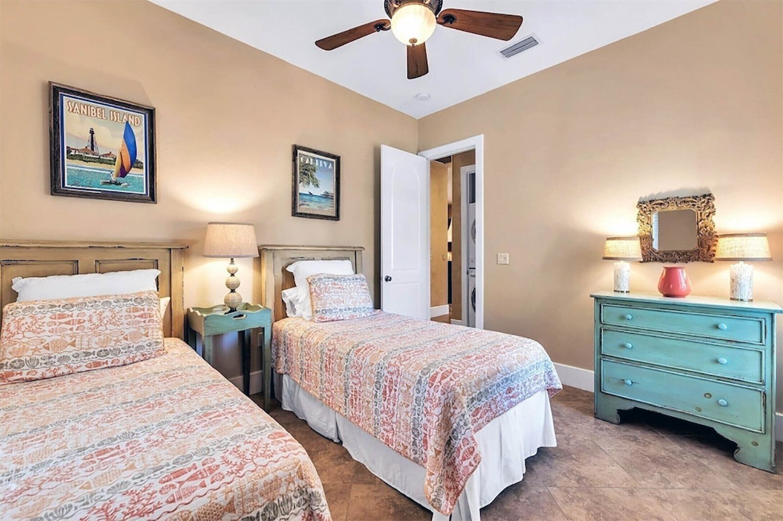 Une chambre avec deux lits, un ventilateur de plafond, une commode et une porte donnant sur un placard.