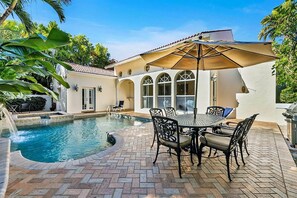 A pool area with a tiled patio, outdoor seating, and a covered table. - Casa Captiva (Captiva)