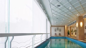 Ein Innenpool mit Glasgeländer, einer Decke mit Gittermuster und einer Wand mit dekorativem Design.