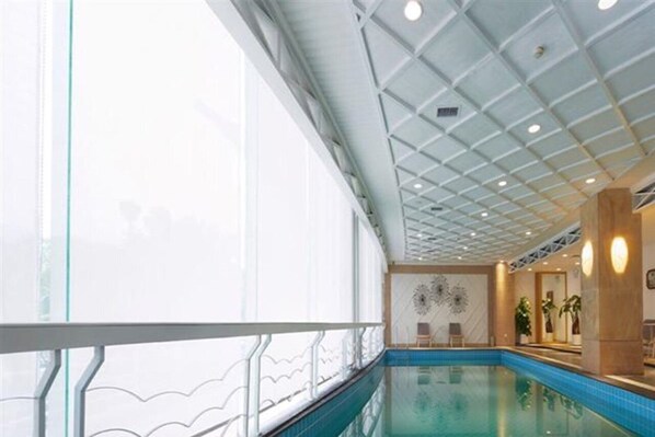 Een binnenzwembad met glazen balustrade, een plafond met rasterpatroon en een muur met decoratief ontwerp.