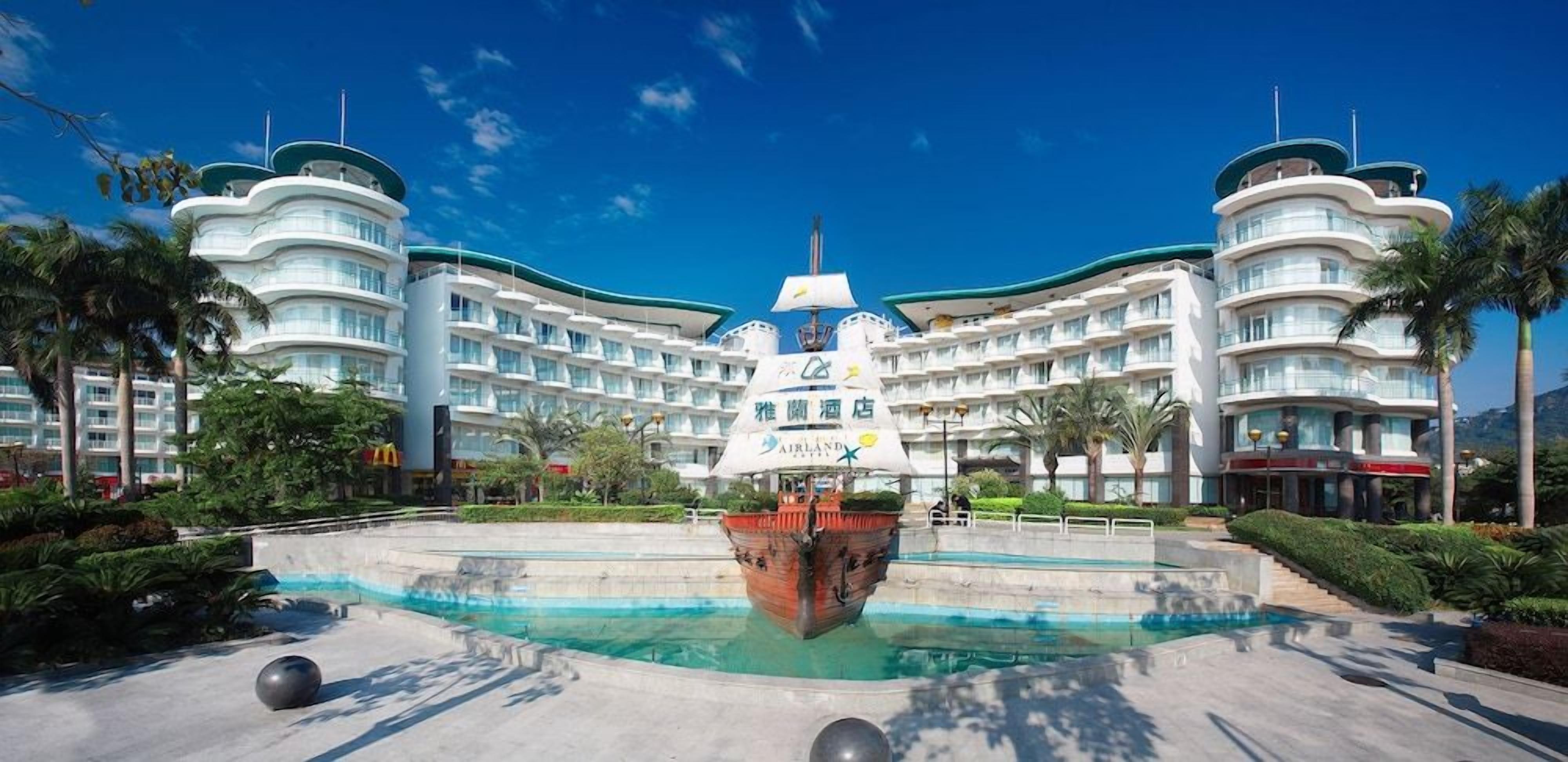 A large, modern hotel with a central courtyard featuring a decorative fountain and a ship model.