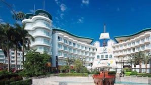 Ein großes, mehrgeschossiges Hotel mit modernem Design, das durch eine markante, gebogene Struktur und eine Flagge auf dem Dach gekennzeichnet ist.
