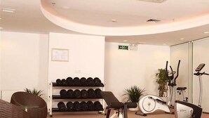 Ein Fitnessraum mit Trainingsgeräten, einer Hantelhantelbank und einem an der Wand befestigten Schild.