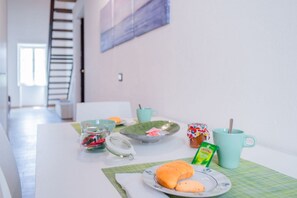 Une table mise pour le petit-déjeuner, avec une assiette de nourriture, une tasse, un pot et un set de table vert.