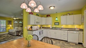 A kitchen with white cabinets, a dining table, and a chandelier. - 'Cloud 9 On The Coast' < 1 Mi to Beach! (Waveland)