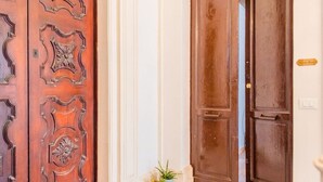 A wooden door with intricate carvings, a potted plant, and a small sign on the wall. - Tempio di Apollo - Ortigia Historic Flat (Siracusa)