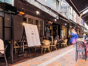 Un espace extérieur aménagé avec des chaises en osier et un présentoir pour les menus.