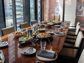 Une table à manger dressée avec différents plats, des verres et des couverts, entourée de chaises.