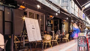 Zona all'aperto con sedute in vimini e un espositore per il menu.