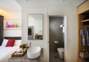 A hotel bathroom with a large mirror, a sink, a toilet, and a shower area. - Ibis Melbourne Central (Melbourne)