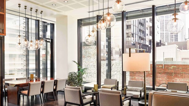 Un interno moderno con zona pranzo, posti a sedere e ampie finestre con vista sulla città.