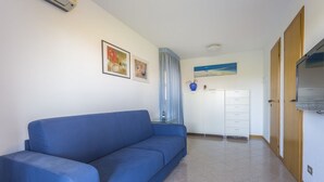 Een kamer met een blauwe bank, een witte kast en een blauw gordijn.