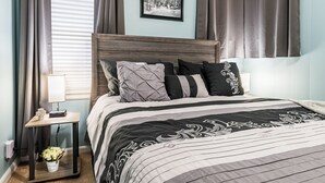 Une chambre à coucher bien rangée, avec un lit, des tables de chevet et un tableau accroché au mur.